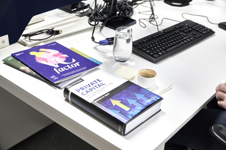 Book titled "Private Markets" on a desk beside a laptop and office workspace, illustrating alternative investments and asset management.